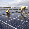 Rohan Dux and Daniel Young install solar panels in Heathwood, Queensland.