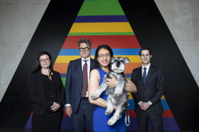 Jo Cooper holds her dog Angus, and stands with her lawyer Sharon Levy from Bartier Perry Lawyers and barristers Robert Newlinds and Robert Pietriche in the foyer of the prestige apartment tower The Horizon. 