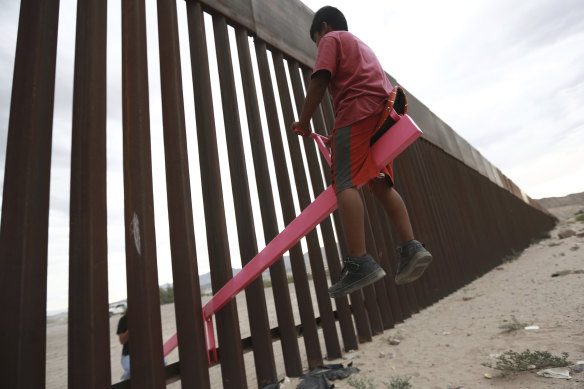 A child plays seesaw installed between the border fence that divides Mexico from the United States in Ciudad de Juarez, Mexico.