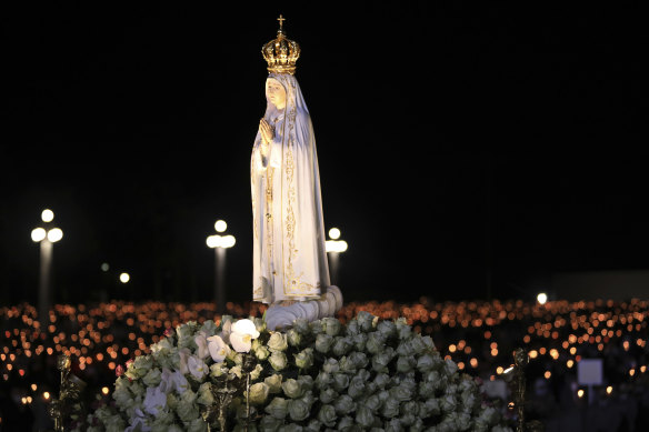 The statue of Our Lady of Fatima is carried past worshippers holding candles in a procession at the Catholic shrine in Fatima, Portugal.