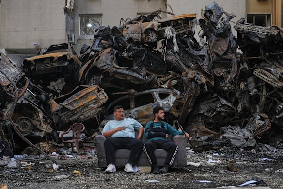 Residents sit in front of burnt vehicles at the site of an Israeli airstrike in central Beirut. Israel will leave Lebanon as soon as Iran leaves Lebanon.