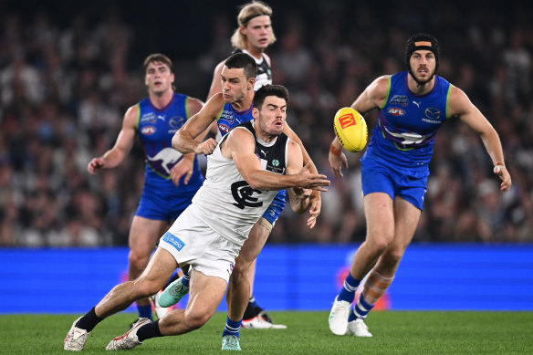 George Hewett of the Blues handballs whilst being tackled by Luke Davies-Uniacke of the Kangaroos.