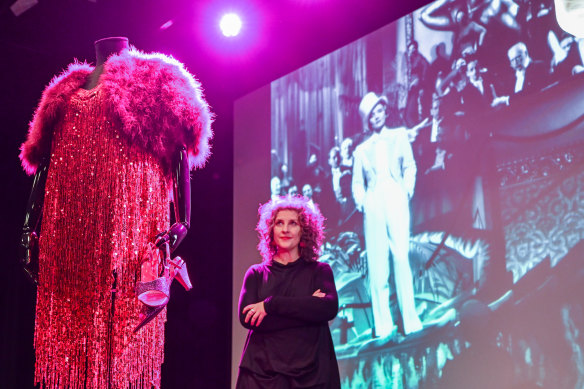 Dr Britt Romstad with one of the costumes from Goddess, ACMI’s  upcoming show about women in film, and Marlene Dietrich on the screen.