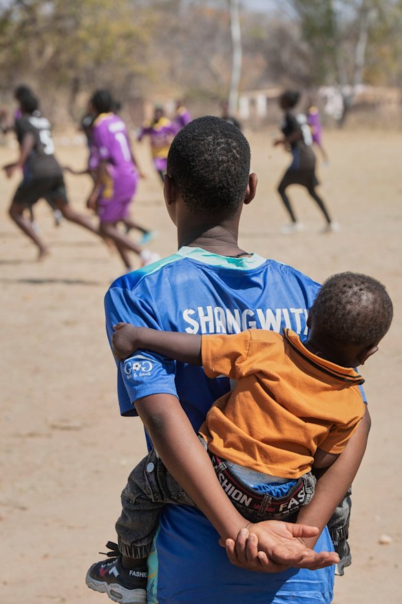 A girl carrying a child on her back watches the tournament.