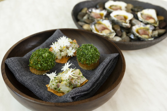 Snacks of cured hiramasa kingfish with phlox flowers and kumquat dressing on tomato crisp; pumpkin with gorgonzola and honey; and wood-fired oysters with pancetta and kombu (rear).