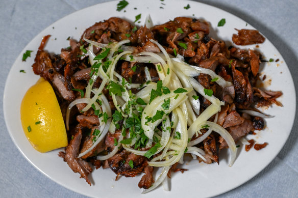 Slow-cooked lamb gyros with raw onion slices and lemon.