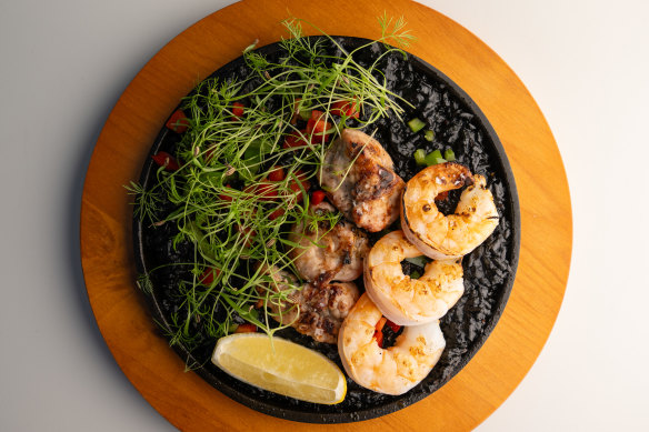 Rice, pitch-black with squid ink, is topped with fat lobes of sweetbread and prawns.