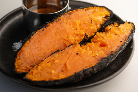 Charcoal sweet potatoes are split open at the table to show off the fluor orange flesh.