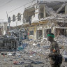 A Somali soldier walks through the scene of a double car-bomb attack in Mogadishu, Somalia.