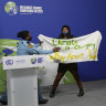 A security guard rushes to apprehend a climate action protester on the stage at the Glasgow summit. 