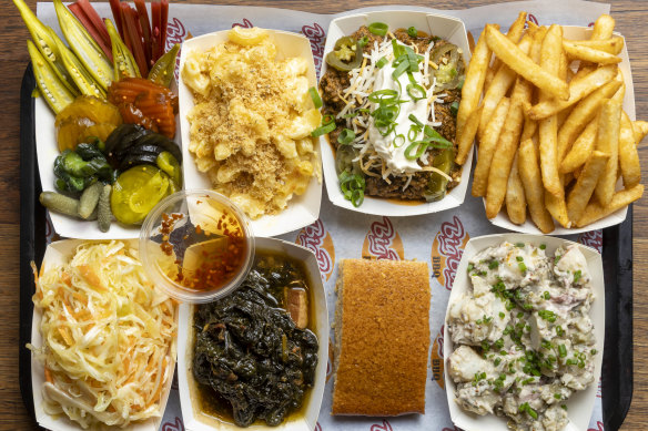 A selection of sides, clockwise from top left: Pickles, macaroni cheese, Texas-style chilli con carne, chips, potato salad, cornbread, greens and coleslaw.