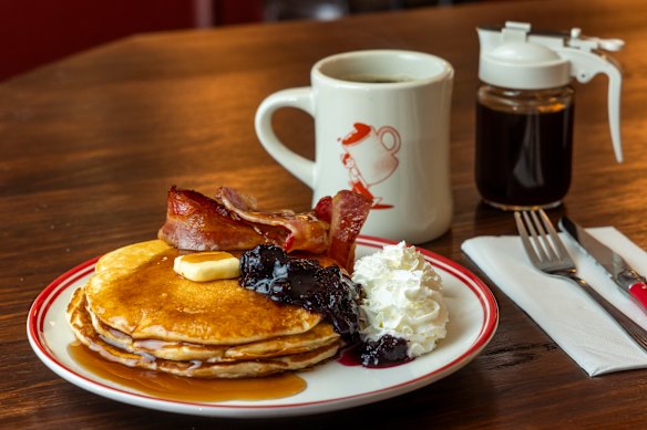 Pancake stack with maple syrup, whipped cream and bacon.
