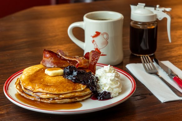 Pancake stack with maple syrup, whipped cream and bacon at JollyGood diner.