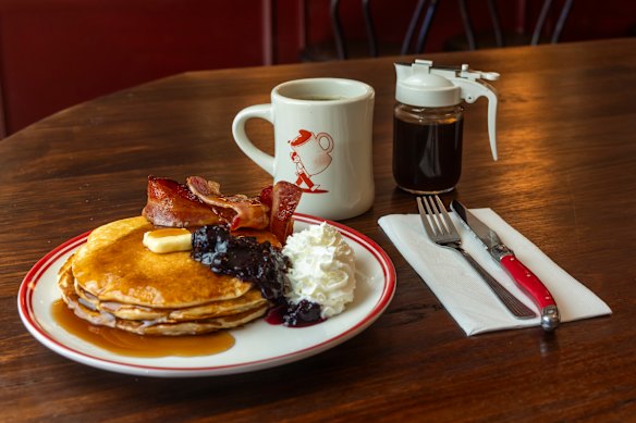 Pancake stack with whipped cream and bacon.