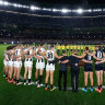 Carlton and Collingwood players, coaches and umpires form a circle as a show of support against gender based violence.