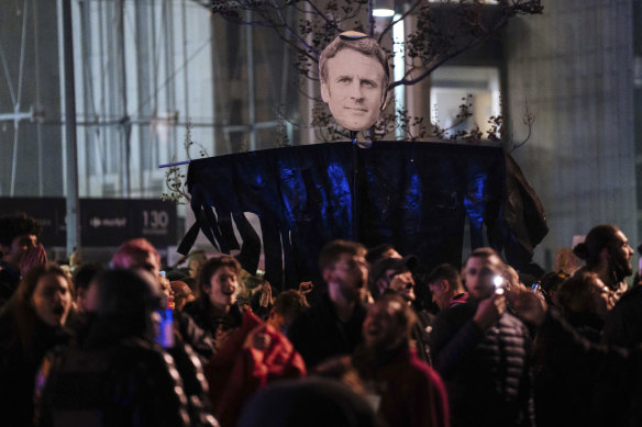 Protesters hold a banner with Emmanuel Macron’s face during a protest in Paris on Saturday.