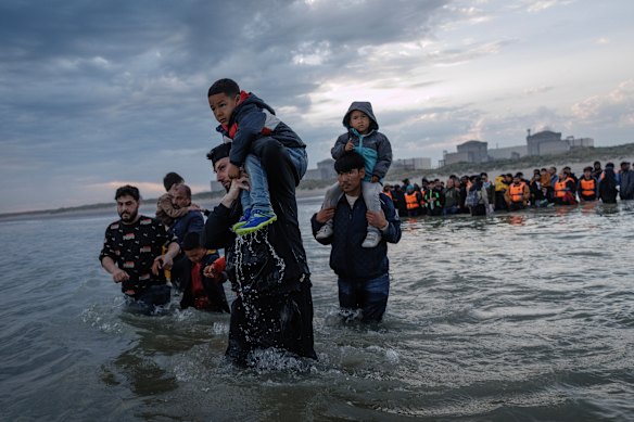 Migrant families wade into the sea at Gravelines, France, in an attempt to board a small boat heading to the UK.