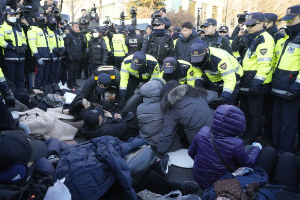 Police officers near the presidential residence in Seoul drag away supporters of impeached President Yoon Suk Yeol.