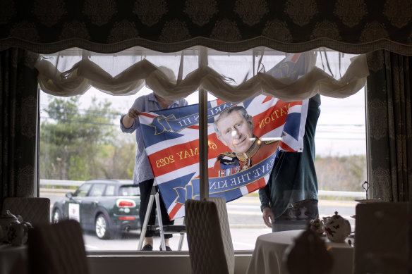 The owners of Val’s English Tea and Pie Shop hang a commemorative flag as they decorate the window ahead of the coronation of King Charles III. 