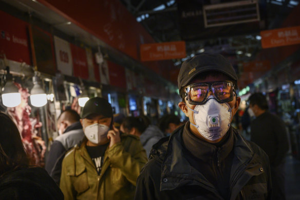 Chinese shoppers wear masks in Beijing. The rate of new coronavirus cases continues to decline in that country. 