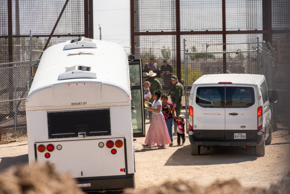 Migrants directed onto US government buses after crossing through a section of the border wall in El Paso, Texas, on the day Title 42 was to expire.