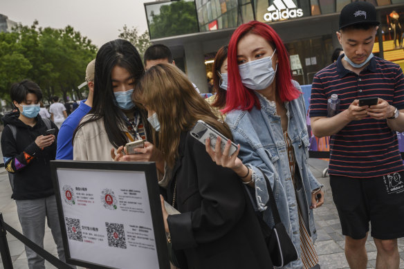 Shoppers scan their local health QR codes from the Beijing Municipality to show security before entering a shopping area.
