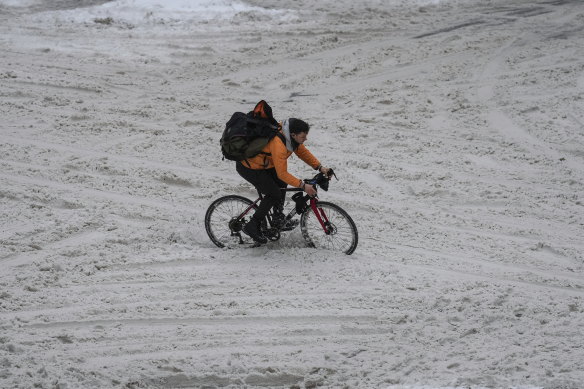A cyclist runs through the snow in downtown Vancouver. 