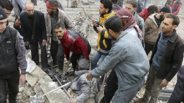 Men pull a survivor from the rubble after airstrikes hit a rebel-held suburb near Damascus on  Monday.