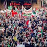 Pro-Palestine and pro-Iran protesters march through Sydney with flags and signs. 