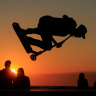 A young man performs a trick on a scooter during the sunset at a skate park on the sea wall of Calais, France.