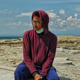 Adam, a 17-year-old from Donggala, in front of the foundation of his home.