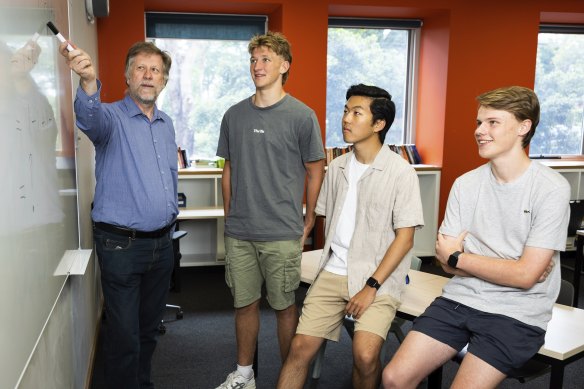 Knox College Year 12 students Harry Cumming, Beau Morrison and Ethan  Huang discuss HSC maths results with teacher Ian Bradford.