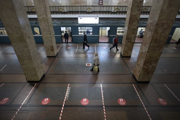 People in Moscow wearing face masks and gloves to protect against coronavirus, observe social distancing guidelines as they walk in the subway.