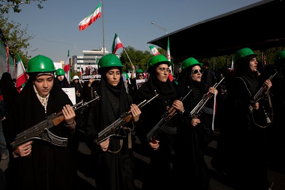 Mulheres seguram rifles e bandeiras durante uma manifestação pró-governo no Dia do Exército Nacional em Teerã, em 17 de abril.
