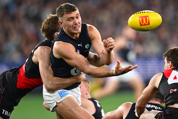 Patrick Cripps of the Blues handballs.