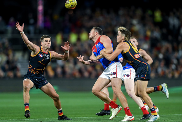 Melbourne’s Steven May gets the ball away as he is tackled by Adelaide’s Jake Soligo.