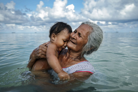 Suega Apelu bathes a child in a lagoon in Tuvalu, one of the Pacific Island nations given aid by Australia.