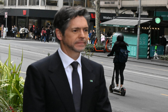 Lord Mayor Nicholas Reece speaks on Wednesday as an e-scooter rides past in the background.