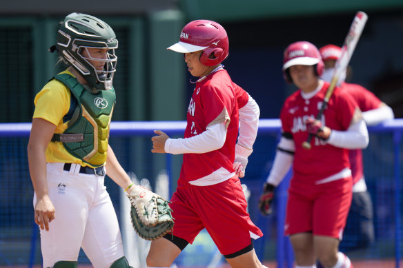 Japan’s Eri Yamada, centre, scores a run during the softball game between Japan and Australia, the Tokyo Olympics opening event, on Wednesday.