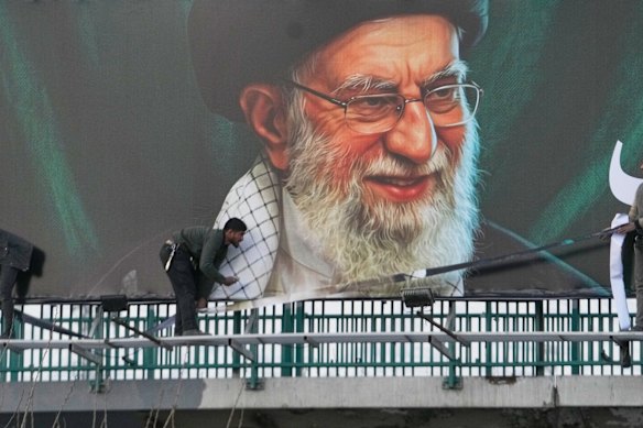 I lavoratori installano un cartellone su un cavalcavia contenente un ritratto del defunto leader supremo iraniano, l'Ayatollah Ali Khamenei.