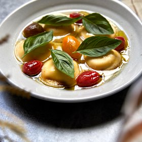 Ricotta ravioli with tomato broth and basil.