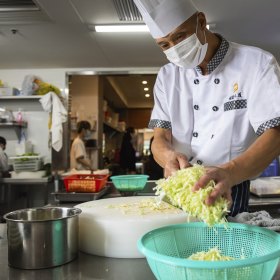 A chef prepares cabbage in the kitchen. 
