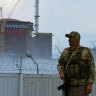 A serviceman with a Russian flag on his uniform stands guard near the Ukrainian Zaporizhzhia Nuclear Power Plant now controlled by Moscow.
