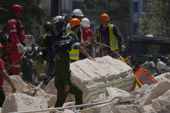 Emergency workers with a stretcher stand amid the rubble.