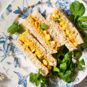 Coronation chicken sandwiches served with watercress garnish and a cup of tea.