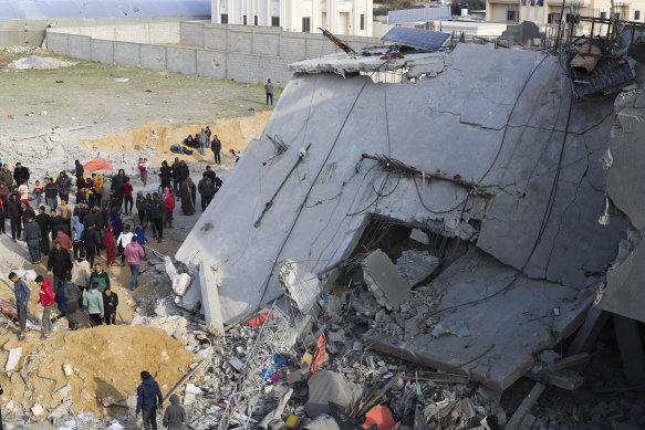 Palestinians look at the destruction after an Israeli strike on a residential building in Rafah, Gaza Strip.