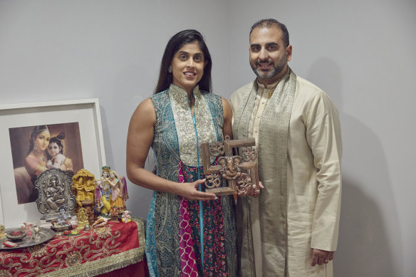 Sheetal Deo and her husband, Sanmeet Deo, hold a Hindu swastika symbol in their home in Syosset, New York.