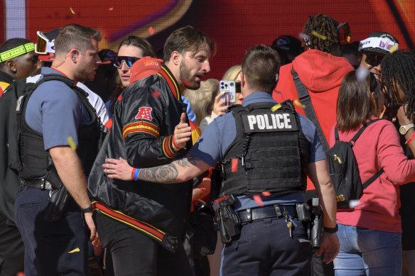 Police escort Kansas City Chiefs tight end Noah Gray and his teammates off the stage after a shooting following their victory parade and rally.