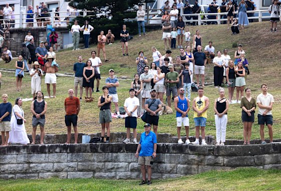 The crowd stands in silence.