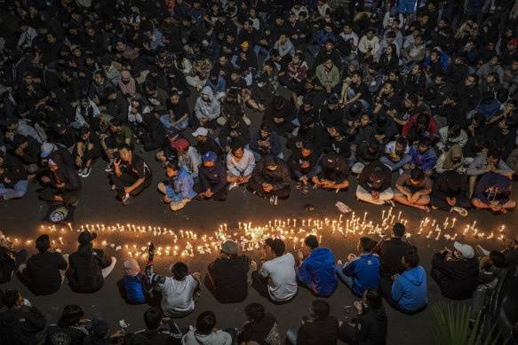 Arema supporters light candles outside the team’s home ground to honour victims. 